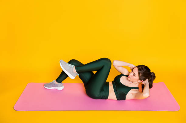 istock Above high angle full body view of nice thin slender sportive girl lying on mat doing crunches isolated on bright yellow color background 1326257598