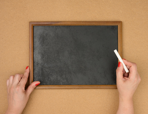 female hands and empty rectangular brown wooden frame on a brown background, copy space