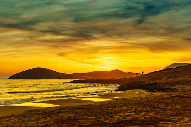 Couple silhouette on seahore at sunset over sea. Seaside landscape. Calblanque Beach, Murcia Spain.