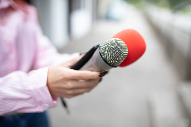 istock Professional journalist at event, holding microphones and recording notes on smartphone 1326261002