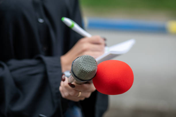 istock Journalist writing notes at news conference, holding microphones 1326261060