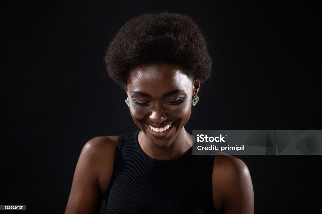 Young black positive african american woman laughing portrait on black background. Young black positive african american woman laughing portrait on black background Dark Stock Photo