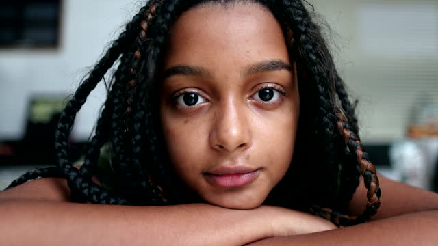 Serious black hispanic girl looking at camera, child portrait face