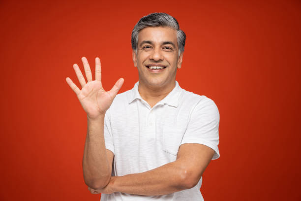 Portrait of mature man standing isolated over red background:- stock photo India, 40-49 Years, Adult, Adults Only, mature men palm of hand photos stock pictures, royalty-free photos & images