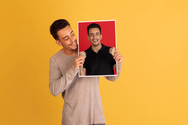 istock Young man holding his portraits isolated over red studio background with copyspace for ad. 1326268791