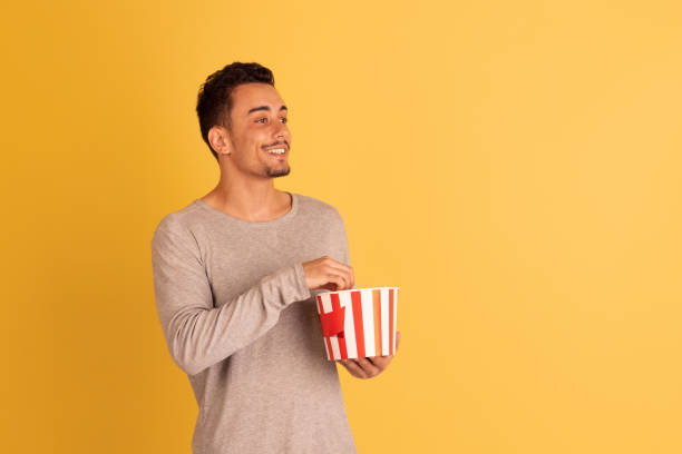 istock Crazy shocked, flying popcorn. Caucasian young man's portrait isolated on blue studio background. Beautiful male model in casual style. 1326268812