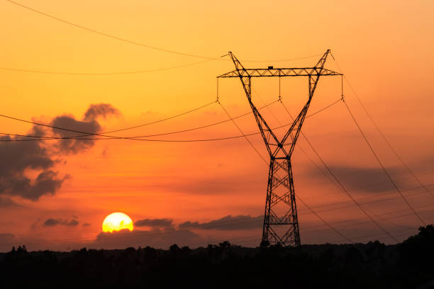 torre de transmisión de electricidad con puesta de sol al fondo. - torre fotografías e imágenes de stock