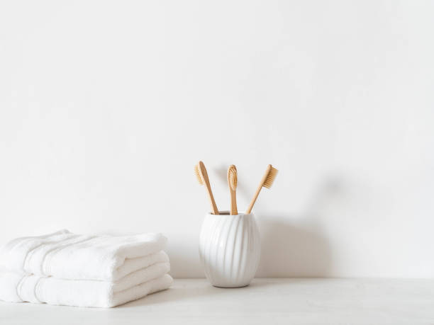 istock Minimal bath background with bamboo toothbrushs in ceramic glass and swhite towels 1326273009