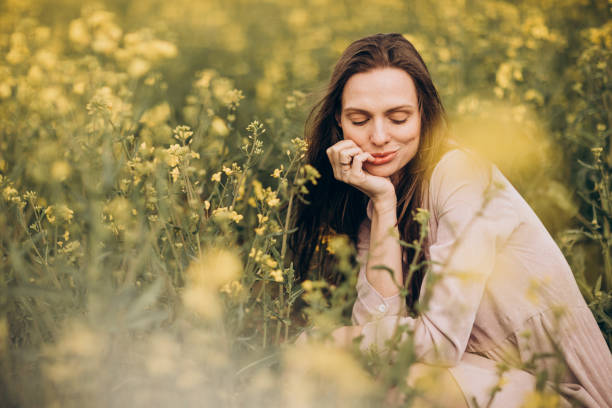 istock Young woman sits in a field with rapeseed. 1326277969