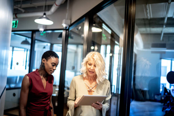istock Business partners walking using digital tablet in corridor 1326277986