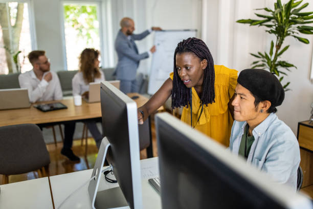 istock Japanese man and Black woman working on computer in office 1326282441