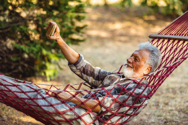 istock Senior Man Lying In Hammock Taking Picture 1326287771