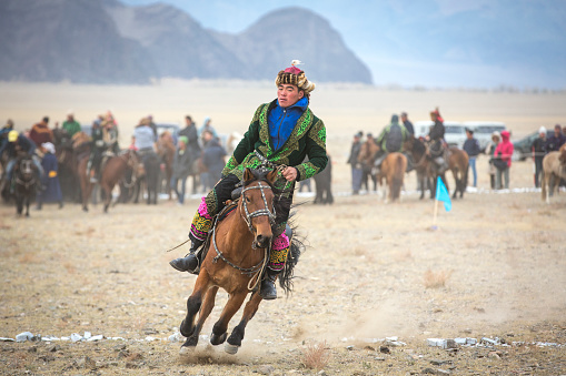 A boy on a Mongol Takhi horse in the serene steppe of Tuv province, Mongolia. A Mongol Takhi horse (Przewalski) is tough for the longer cold winter months in the country.  The steppe is serene and vast.
