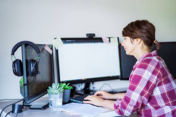 istock Side view woman working on pc with few monitors at home working space. Remote work concept. Freelancer workspace. Selective focus. Copy space. 1326291605