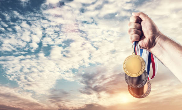 mano con medallas celebrando el éxito de los juegos olímpicos - medallista fotografías e imágenes de stock