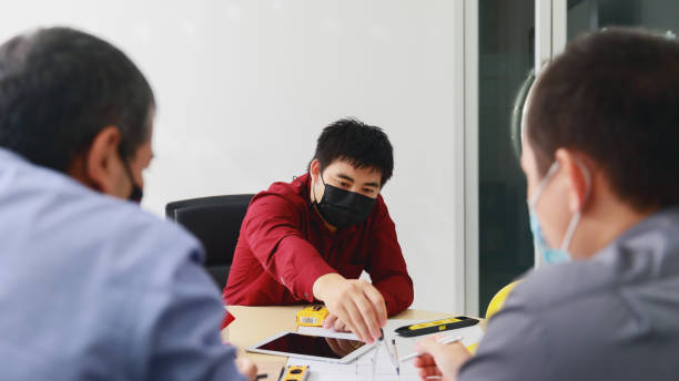 istock Confident team of architect and engineer wearing protective masks working together in a office. Architectural concept. Social distance practice prevent coronavirus COVID-19. 1326293202