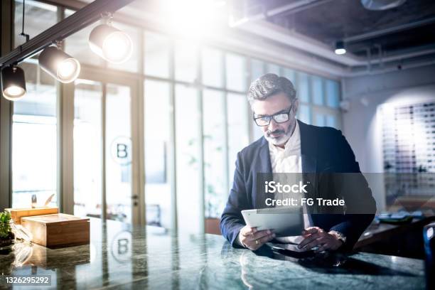 Mid Adult Man Working Using Digital Tablet Stock Photo - Download Image Now - Investment, CEO, Digital Tablet