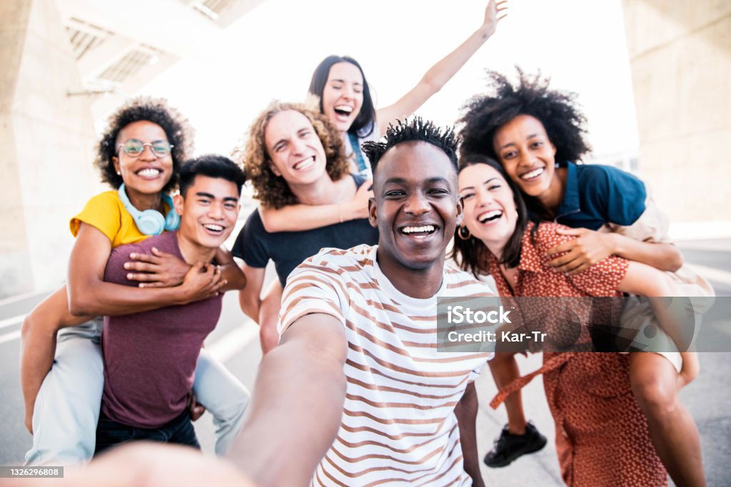 Multicultural happy friends having fun taking group selfie portrait on city street - Young diverse people celebrating laughing together outdoors - Happy lifestyle concept Friendship Stock Photo