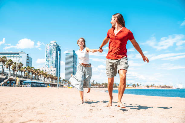 happy couple in love enjoying vacation running on tropical beach - boyfriend and girlfriend having fun outdoor on summer holiday - vacations and lifestyle concept - tourists couple barcelona imagens e fotografias de stock