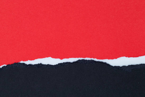 istock Sheets of red and white paper with ragged edges on black background with space for text 1326297959