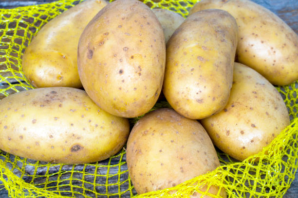 istock Heap of raw potatos in yellow string bag, 1326302946