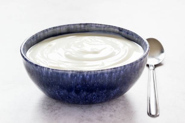 istock Bright high key image of plain yogurt in blue bowl with spoon aside 1326304024