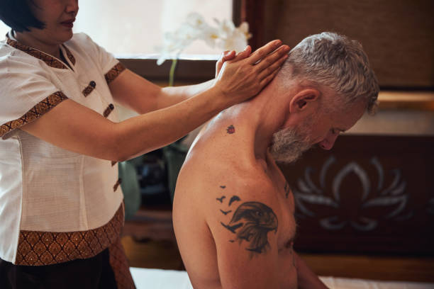 tattoed mature man during thai therapy in studio - tattoo japanese culture women asian ethnicity imagens e fotografias de stock