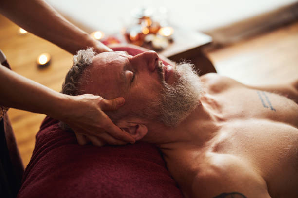 homem grisalho bonito desfrutando massagem na cabeça dentro de casa - massaging relaxation indoors traditional culture - fotografias e filmes do acervo