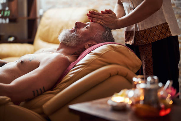 uomo tranquillo durante il massaggio manuale alla testa in studio - massaging relaxation indoors traditional culture foto e immagini stock