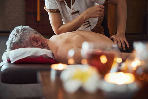 terapeuta manual tailandês curando homem de volta ao estúdio - massaging relaxation indoors traditional culture - fotografias e filmes do acervo