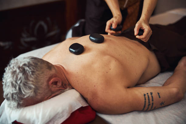 man during back massage with stones in studio - tattoo japanese culture women asian ethnicity imagens e fotografias de stock