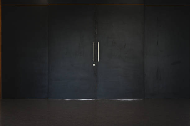 istock Large black sliding wooden door closed shut. Empty room interior. 1326306314