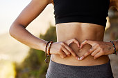 istock Cropped shot of a young woman forming a heart shape over her stomach 1326307899