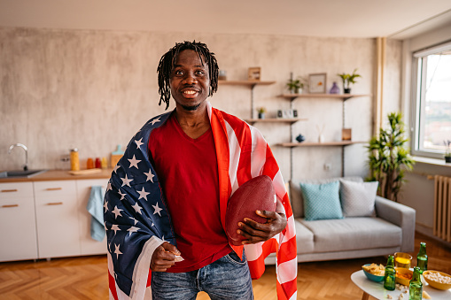 USA American football fan watching a football game at home and cheering.