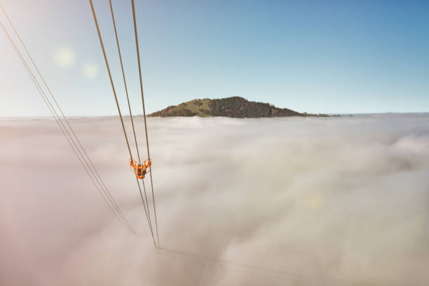 The steel ropes of a cable car disappear in the fog In the background you can still see the Hundwilerhöhe mountain. The cable car is the one to Kronberg in Appenzllerland, Switzerland, on a foggy autumn day. appenzell stock pictures, royalty-free photos & images