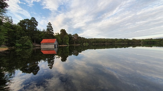 Clouds reflected in lake with old fishing cabin with red roof