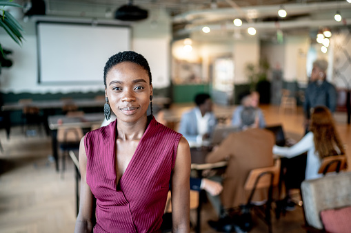 Portrait of a young business woman with coworkers on the background