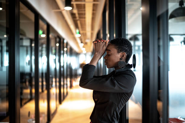 обеспокоенная молодая бизнес-женщина в офисе коридора - women sadness african ethnicity african descent стоковые фото и изображения