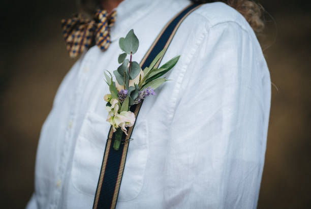 Close up of groom dressed in a casual suit at his wedding Wearing boutonnière flowers and a bow tie buttonhole flower stock pictures, royalty-free photos & images