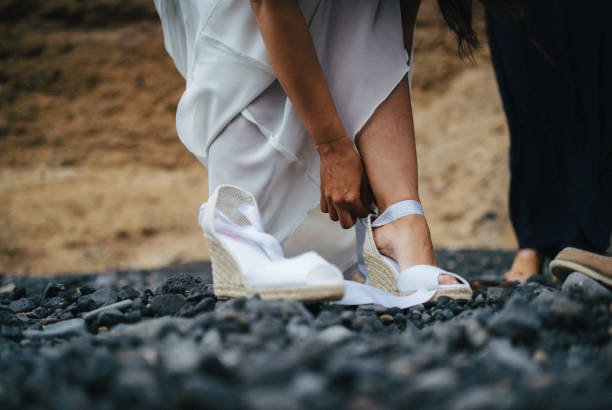 istock Bride puts on heels before getting married on rocky beach 1326322648