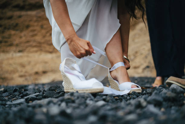 Bride puts on heels before getting married on rocky beach