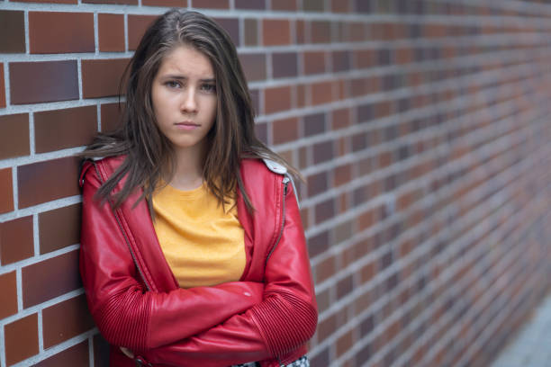 Unhappy teenager Portrait of a sad teenage girl in front of a brick wall sad 15 years old girl stock pictures, royalty-free photos & images