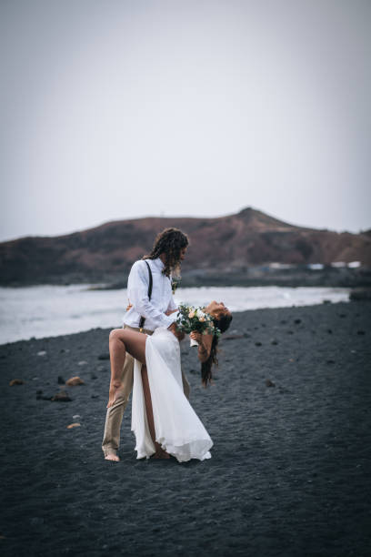 istock Newlyweds dance on rocky beach after wedding 1326324421