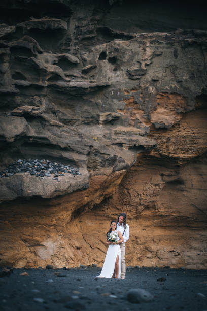 istock Newlyweds relax after wedding on rocky beach 1326324985