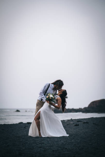 istock Newlyweds dance on rocky beach after wedding 1326325025