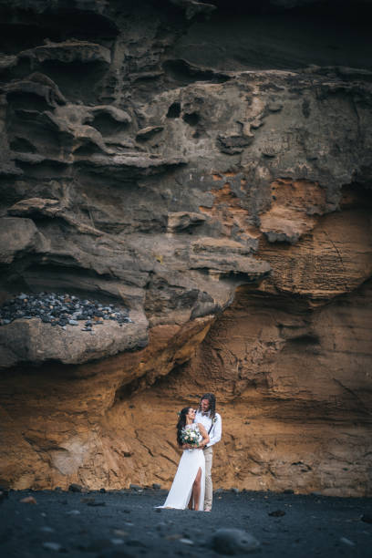 istock Newlyweds relax after wedding on rocky beach 1326325036