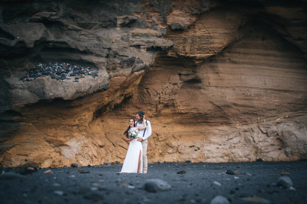 istock Newlyweds relax after wedding on rocky beach 1326325128