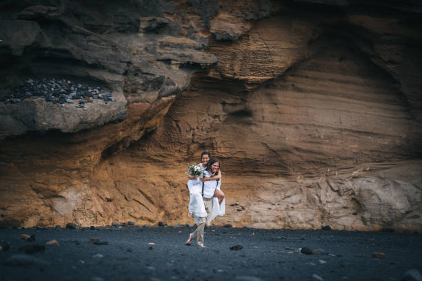 istock Groom carries bride on his back after beach wedding 1326325130