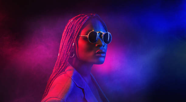 colorida toma filtrada de neón de una hermosa joven afro posando en el estudio - currency women luxury wealth fotografías e imágenes de stock