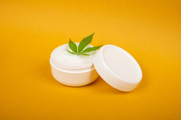 cannabis cosmetics , natural marijuana cream and green leaf on beauty yellow background stock photo